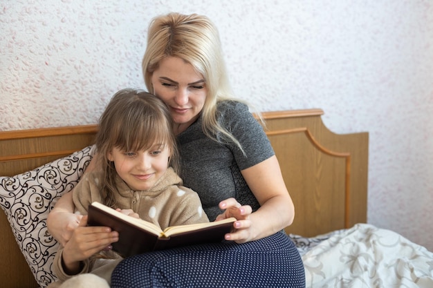 Mutter mit Lesebuch des kleinen Mädchens im Sofa