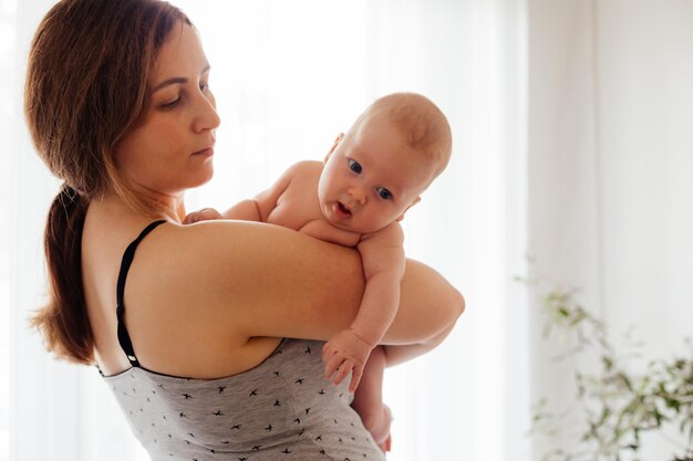 Mutter mit nacktem Neugeborenen auf beleuchtetem weißem Hintergrund