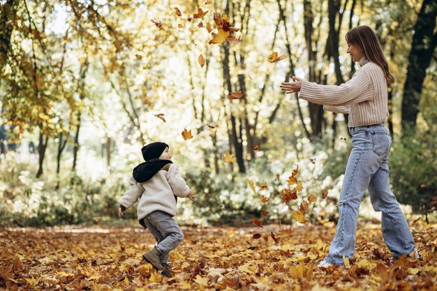 Mutter mit Sohn hat Spaß im herbstlichen Park und spielt mit Blättern