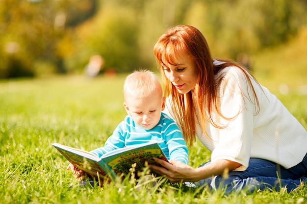 Mutter mit Sohn liest Buch im Park