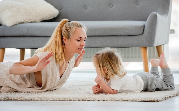 Mutter mit Sohn machen gemeinsam Übungen, die zu Hause auf dem Boden liegen