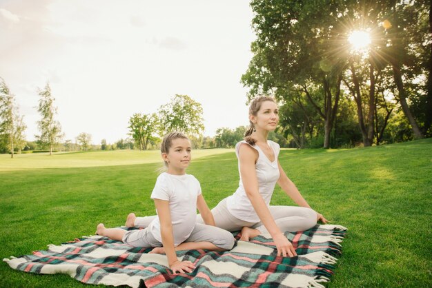 Mutter mit Tochter, die Yogaübung macht