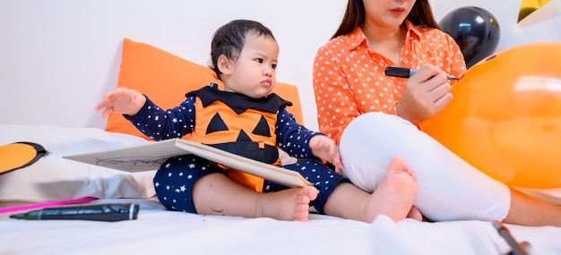 Mutter mit Tochter im Kostüm zum Feiern von Halloween zu Hause. Kind mit Mama in der Schlafzimmerdekoration