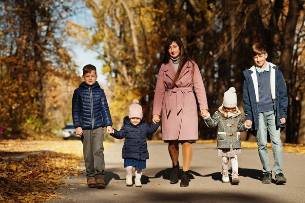 Mutter mit vier Kindern im Herbstpark. Familienspaziergang im Herbstwald.