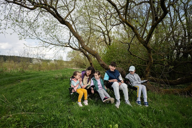 Mutter mit vier Kindern sitzt auf Stühlen im Frühlingswald