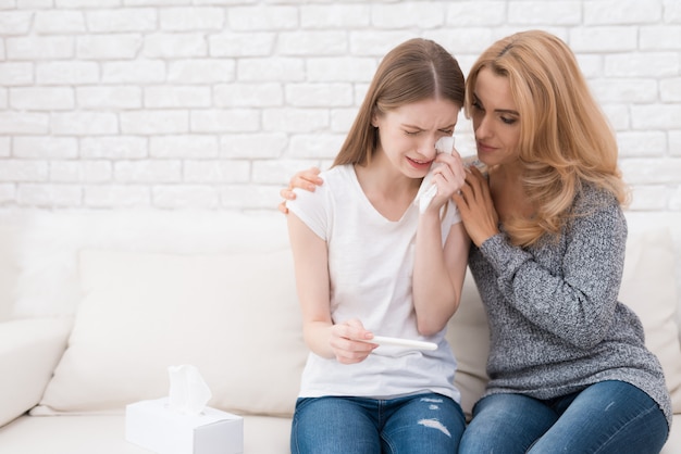 Mutter nahe umgekippter Tochter mit Schwangerschaftstest.