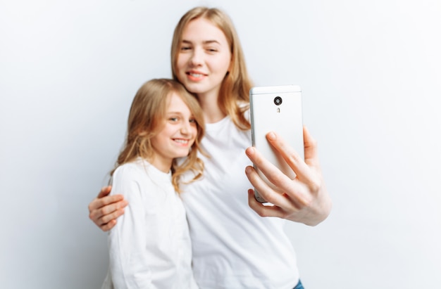 Mutter oder ältere Schwester macht Selfie kleines Mädchen, glückliche Familie