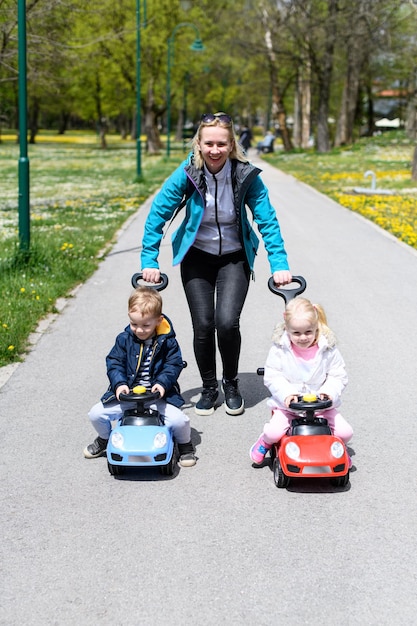 Foto mutter rollt ihre kinder auf einem spielzeugauto