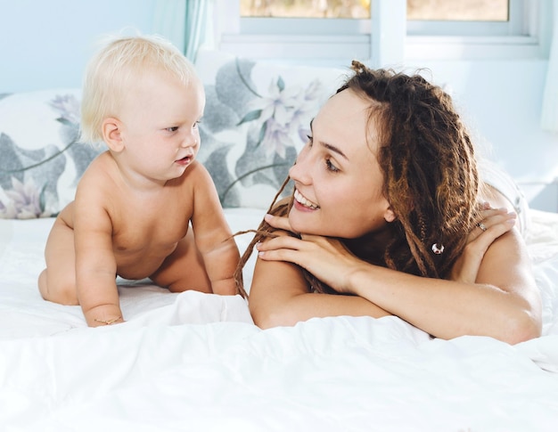 Mutter schaut sich ihre nackte Tochter zu Hause im Bett an