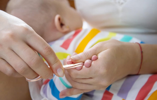 Mutter schneidet die Nägel des kleinen Babys Selektiver Fokus