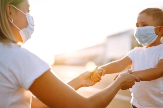 Mutter setzt bei Sonnenuntergang ihre medizinische Babymaske auf.