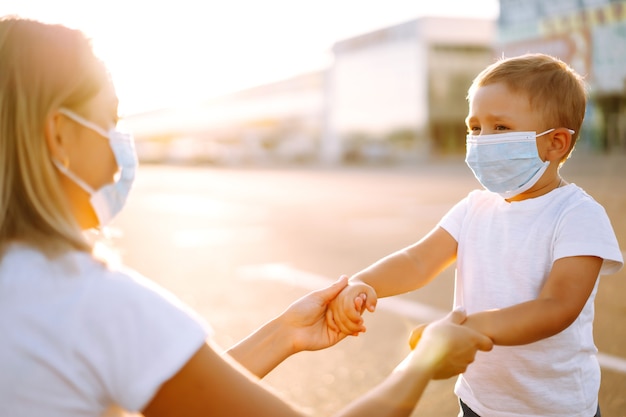 Mutter setzt bei Sonnenuntergang ihre medizinische Babymaske auf.