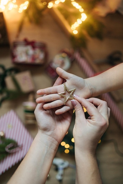 Mutter setzte Weihnachtsbaum Spielzeug auf Tochter Hand Hintergrund von Weihnachten Licht und Dekorationen