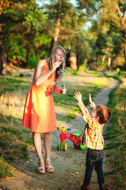 Mutter, Sohn spielen auf dem Spielplatz, lachen, haben Spaß beim Spaziergang. Glücklicher Familienlebensstil. Kinder