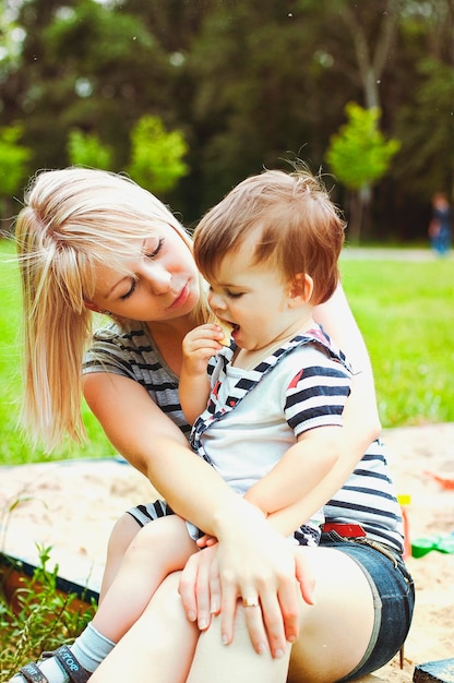 Mutter, Sohn spielen auf dem Spielplatz und lachen beim Sommerspaziergang. sonniger Tag. Familienurlaub. Kinder