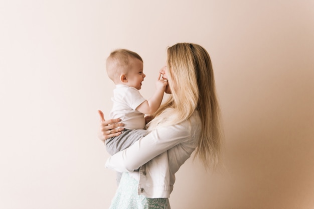 Mutter spielt mit Baby, glückliche Familie, die Spaß drinnen hat, fröhliches süßes Kinderporträt, Mutter und Kind, gesundes Kleinkind, hebendes Werfen, das das Halten des Spiels anhebt