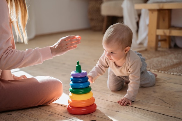 Mutter spielt mit einem 1-jährigen Baby-Pyramidenspiel, das zu Hause sitzt