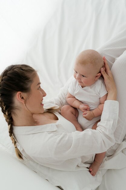 Foto mutter spielt mit einem viermonatigen jungen auf weißem hintergrund, küsst, hält, umarmt, liebt das gesicht.