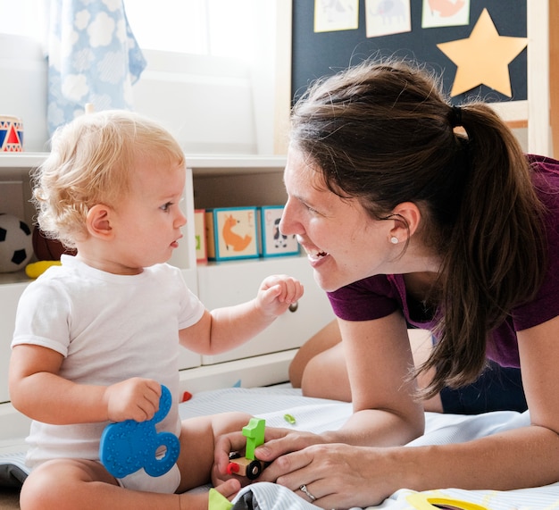 Foto mutter spielt mit ihrem baby auf dem boden