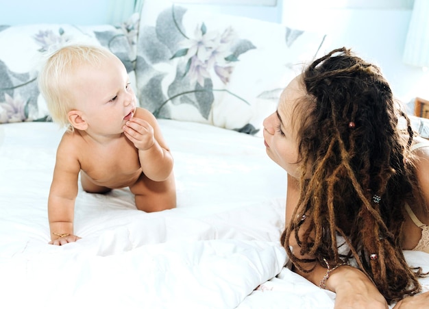 Mutter spielt mit nackter Tochter zu Hause im Bett