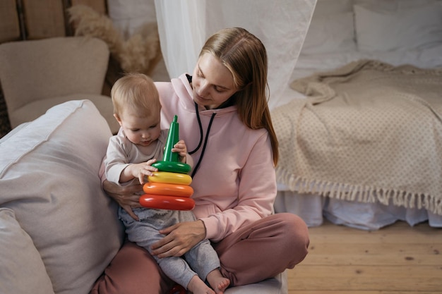 Foto mutter spielt spielzeug mit ihrem süßen baby zu hause baby-entwicklungskonzept