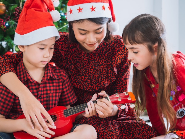 Mutter spielte am Weihnachtstag mit Jungen und Mädchen Gitarre