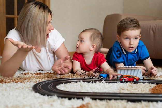 Mutter, Tochter und Sohn spielen Rennen auf dem Teppich