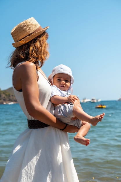 Foto mutter trägt einen hut mit ihrem baby in cala montjoi, strand des parc natural del cap creus, gerona, costa brava von katalonien im mittelmeer. spanien