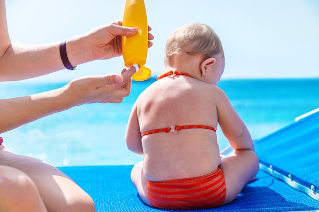 Mutter trägt Sonnencreme auf ein Baby auf