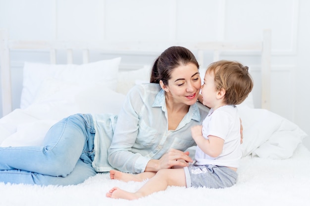 Mutter umarmt Baby zu Hause auf dem Bett das Konzept der Familie und Kinder Muttertag