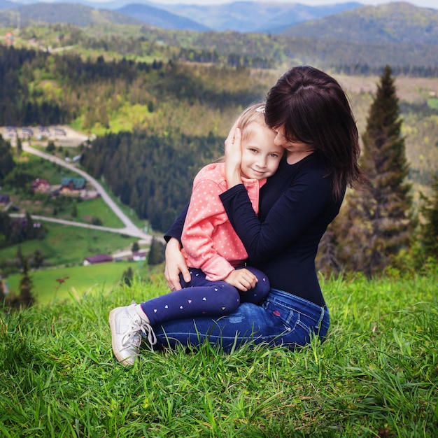 Mutter umarmt eine kleine Tochter am Gipfel des Berges.