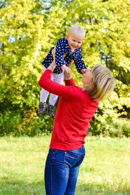 Foto mutter umarmt ihr baby mädchen geht im herbstpark stilvolle blonde frau mit einem kind gegen