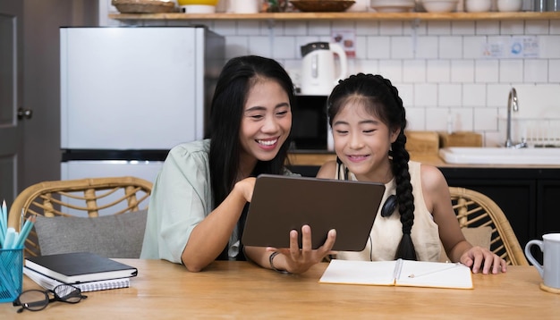 Mutter und asiatisches kind kleines mädchen lernen und betrachten laptop-computer machen hausaufgaben lernen mit online-bildung elearning-systemkinder videokonferenz mit lehrer tutor zu hause