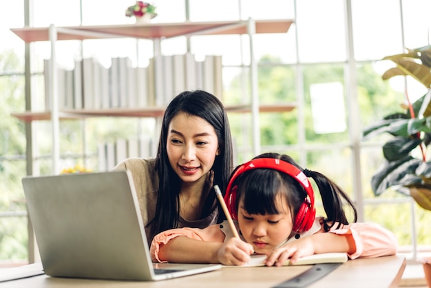 Mutter und asiatisches Kind kleines Mädchen lernen und betrachten Laptop-Computer machen Hausaufgaben studieren Wissen mit Online-Bildung E-Learning-System
