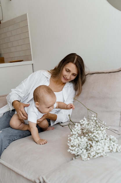 mutter und baby auf dem bett mit einem blumenstrauß aus weißen blumen