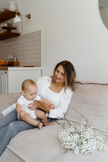 mutter und baby auf dem bett mit einem blumenstrauß aus weißen blumen