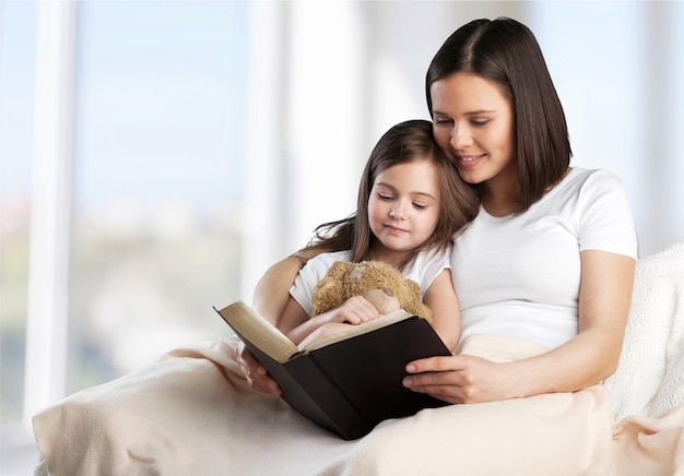 mutter und baby lesen ein buch im bett, bevor sie schlafen gehen