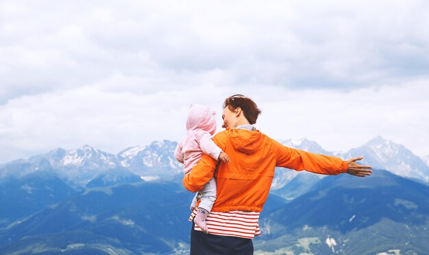 Mutter und baby mit bergen auf einem hintergrund. familie verbringen sommerferien in den dolomiten, italien, europa. blick auf bruneck und das pustertal vom gipfel des kronplatzes.