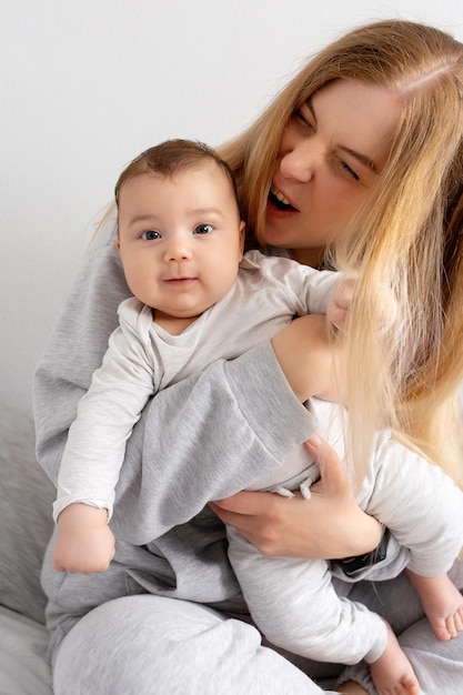 Mutter und Baby spielen auf dem Bett Mutter und Sohn glückliche Familie schönes blondes Mädchen und süßes Baby zu Hause