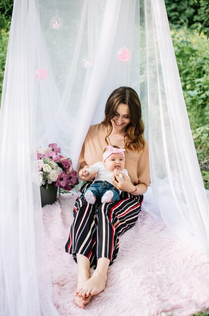 Mutter und Baby spielen und lächeln im Garten