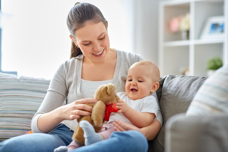 Foto mutter und baby spielen zu hause mit einem teddybären
