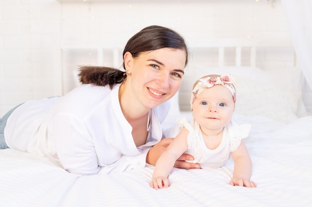 Mutter und Baby umarmen sich auf einem weißen Baumwollbett zu Hause Mutterliebe und Fürsorge