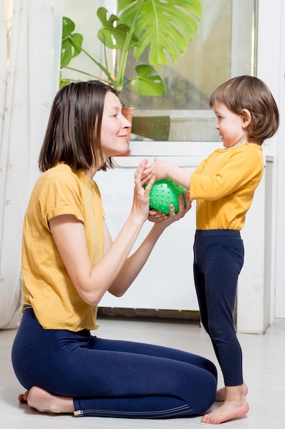 Mutter und ein kleines Kind spielen zu Hause mit einem Ball Aktivitäten zu Hause
