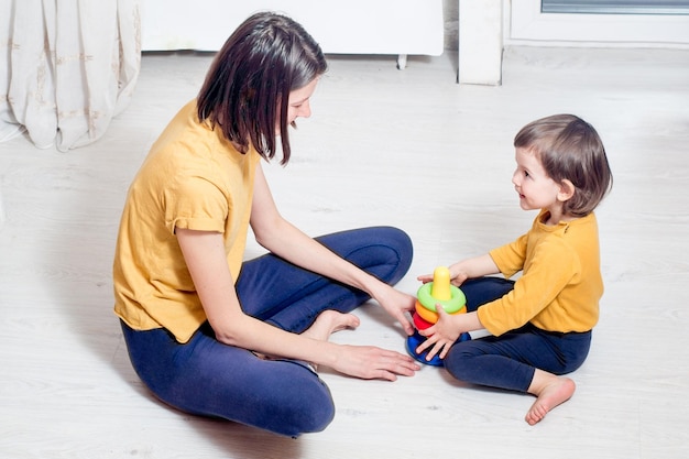 Mutter und ein kleines Kind spielen zusammen Spielzeug auf dem Boden Aktivitäten zu Hause