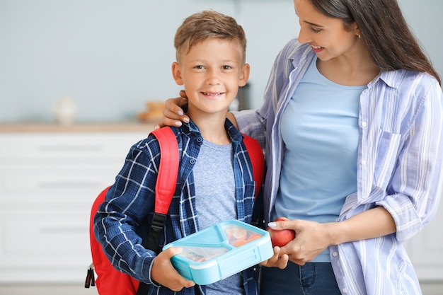 Mutter und ihr kleiner Sohn mit Brotdose vor der Schule