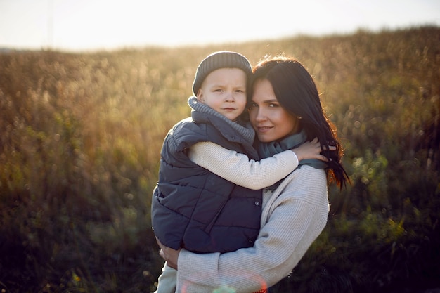 Mutter und ihr Sohn stehen bei Sonnenuntergang auf einem Feld mit trockenem Gras