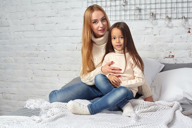 Mutter und ihr Tochtermädchen spielen und umarmen sich auf dem Bett