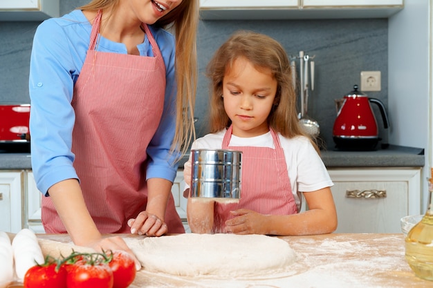 Mutter und ihre kleine Tochter bereiten Teig in der Küche vor