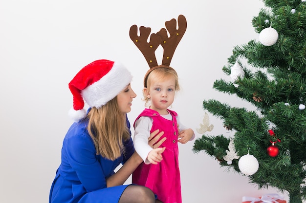 Mutter und ihre kleine Tochter neben dem Weihnachtsbaum