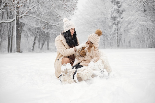 Mutter und ihre kleine Tochter spielen am Wintertag im Freien